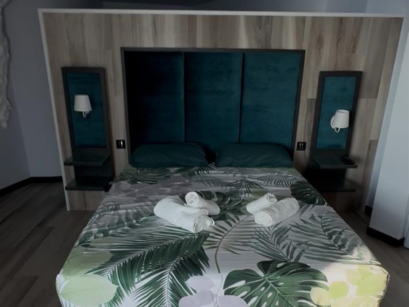 Dormitorio con cabecero tapizado y toallas dobladas sobre la cama