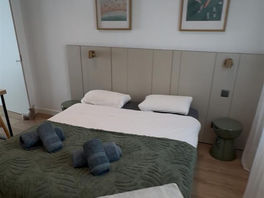 Cama vestida con ropa limpia y toallas presentadas para los huéspedes