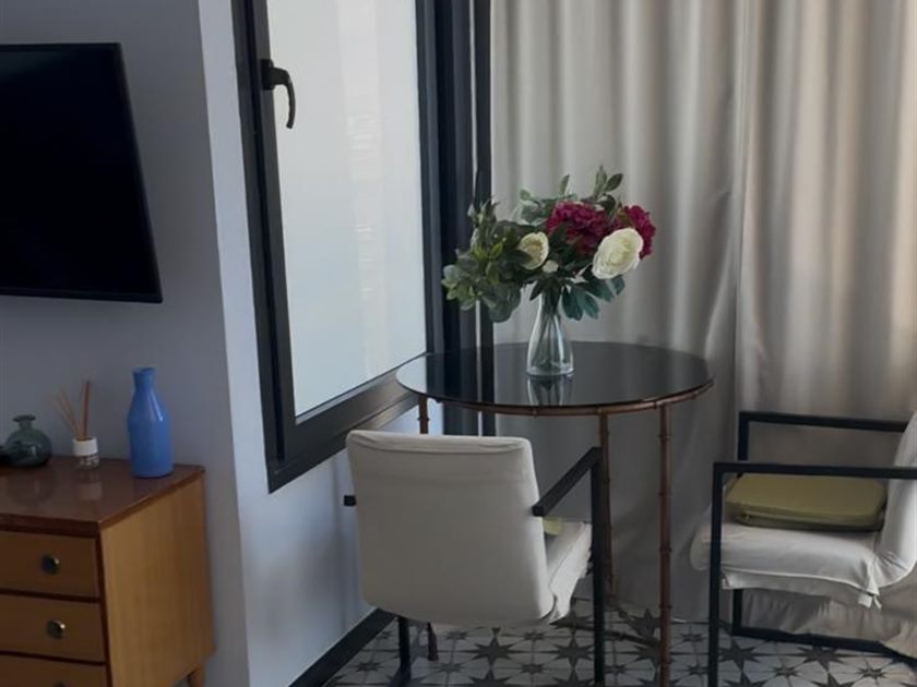 Rincón con mesa de cristal y flores frescas junto a la ventana
